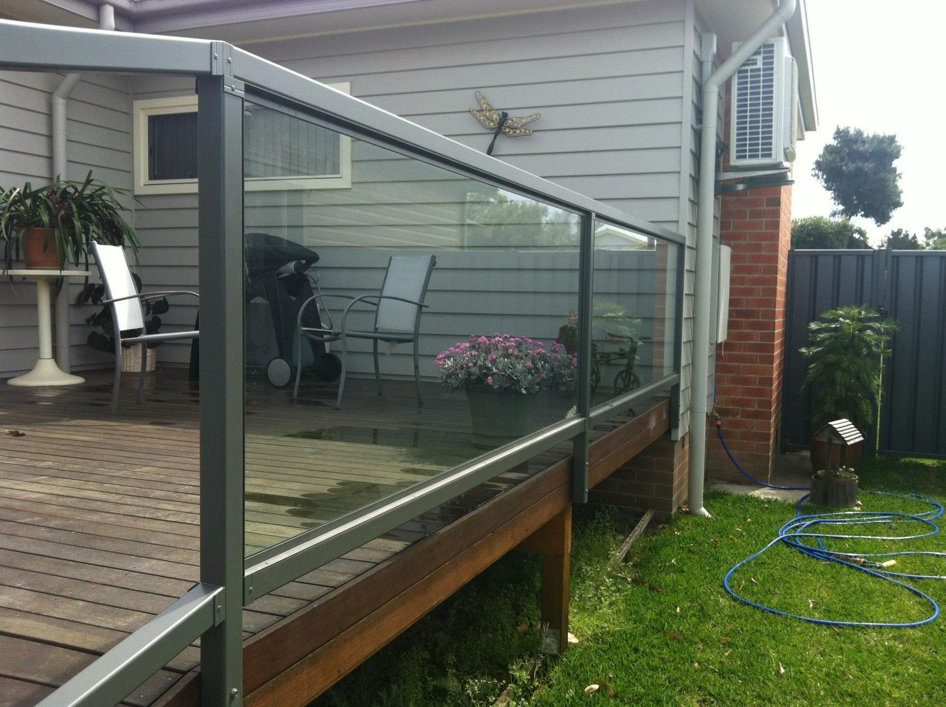 A white patio cover is being installed on the side of a brick house.