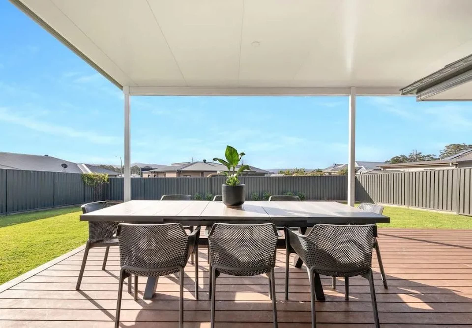 A white patio cover is being installed on the side of a brick house.