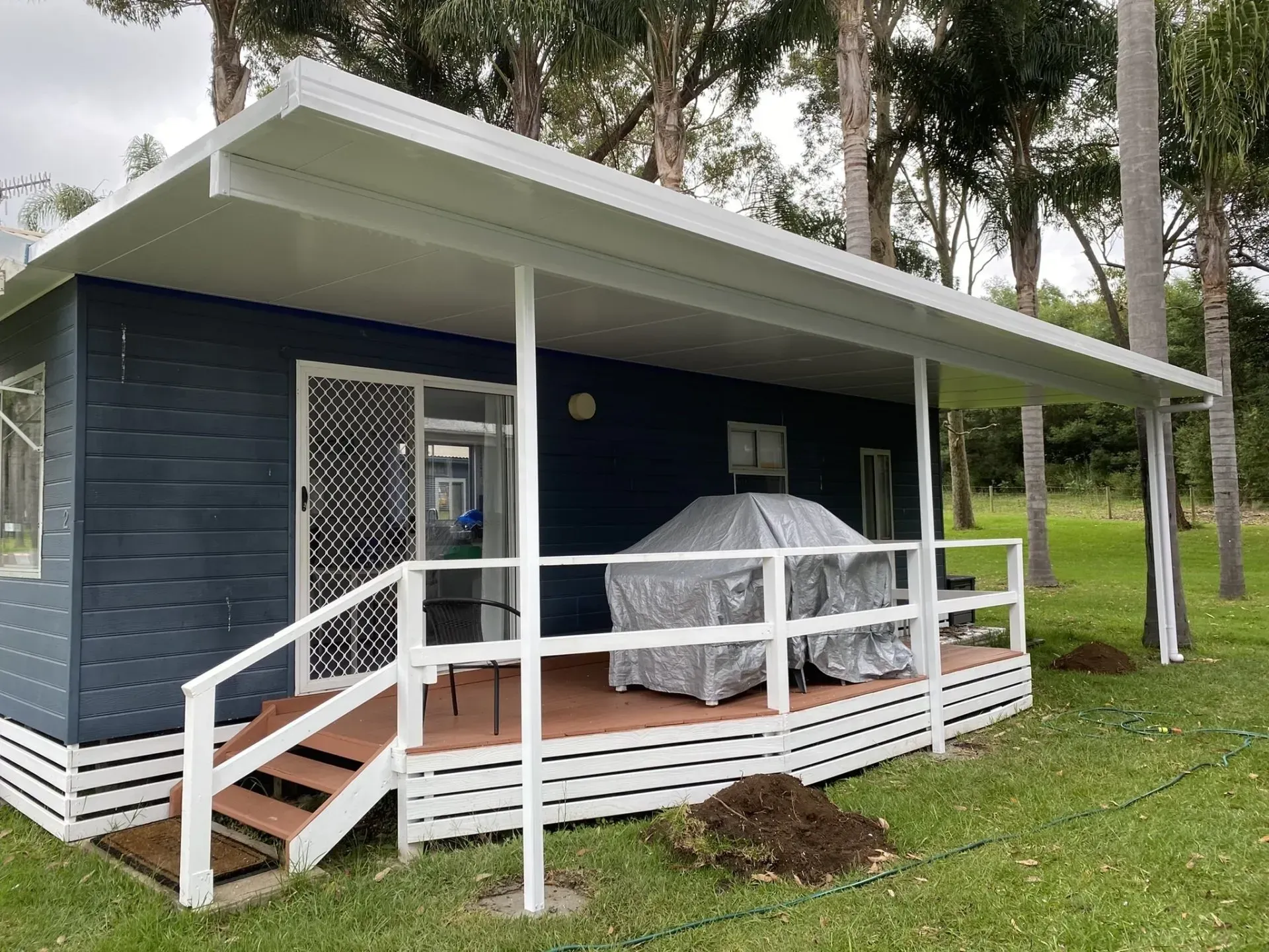 A white patio cover is being installed on the side of a brick house.