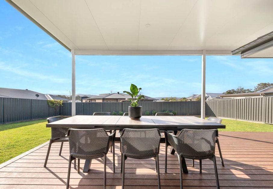 A white patio cover is being installed on the side of a brick house.
