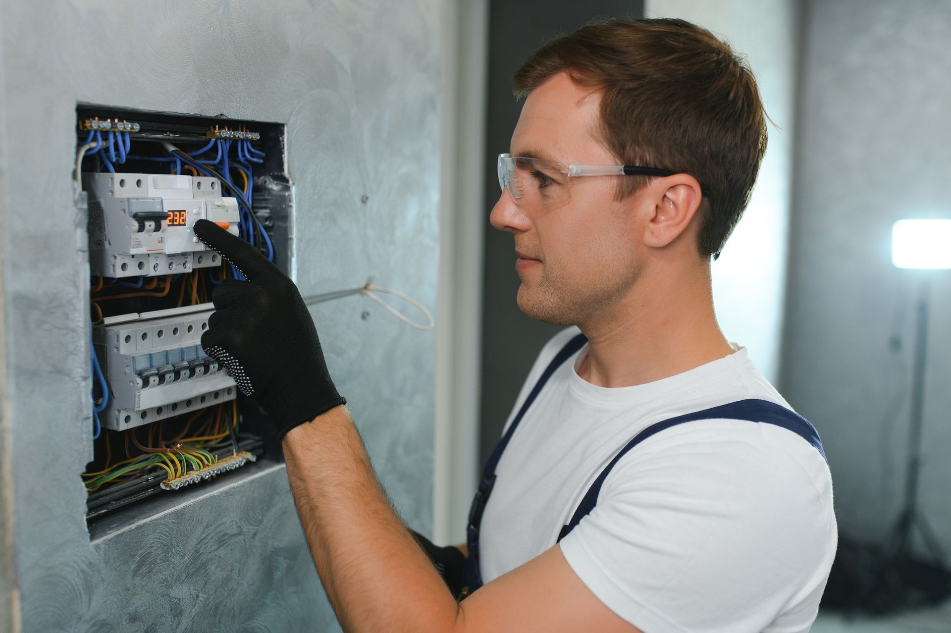 A man is working on an electrical box on a wall.