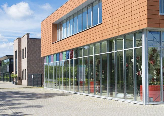 A two-story building with a terracotta-tiled upper level and a floor-to-ceiling glass storefront on the ground floor.