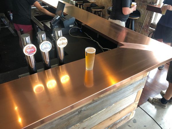 A copper bar with a glass of beer on it.