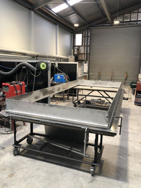 A large piece of metal is sitting on top of a cart in a factory.