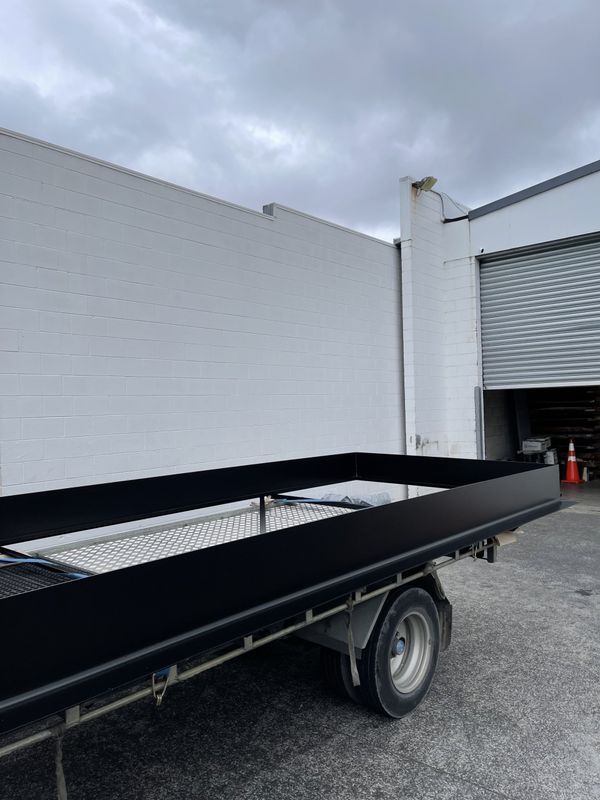 A black flatbed truck is parked in front of a white building.
