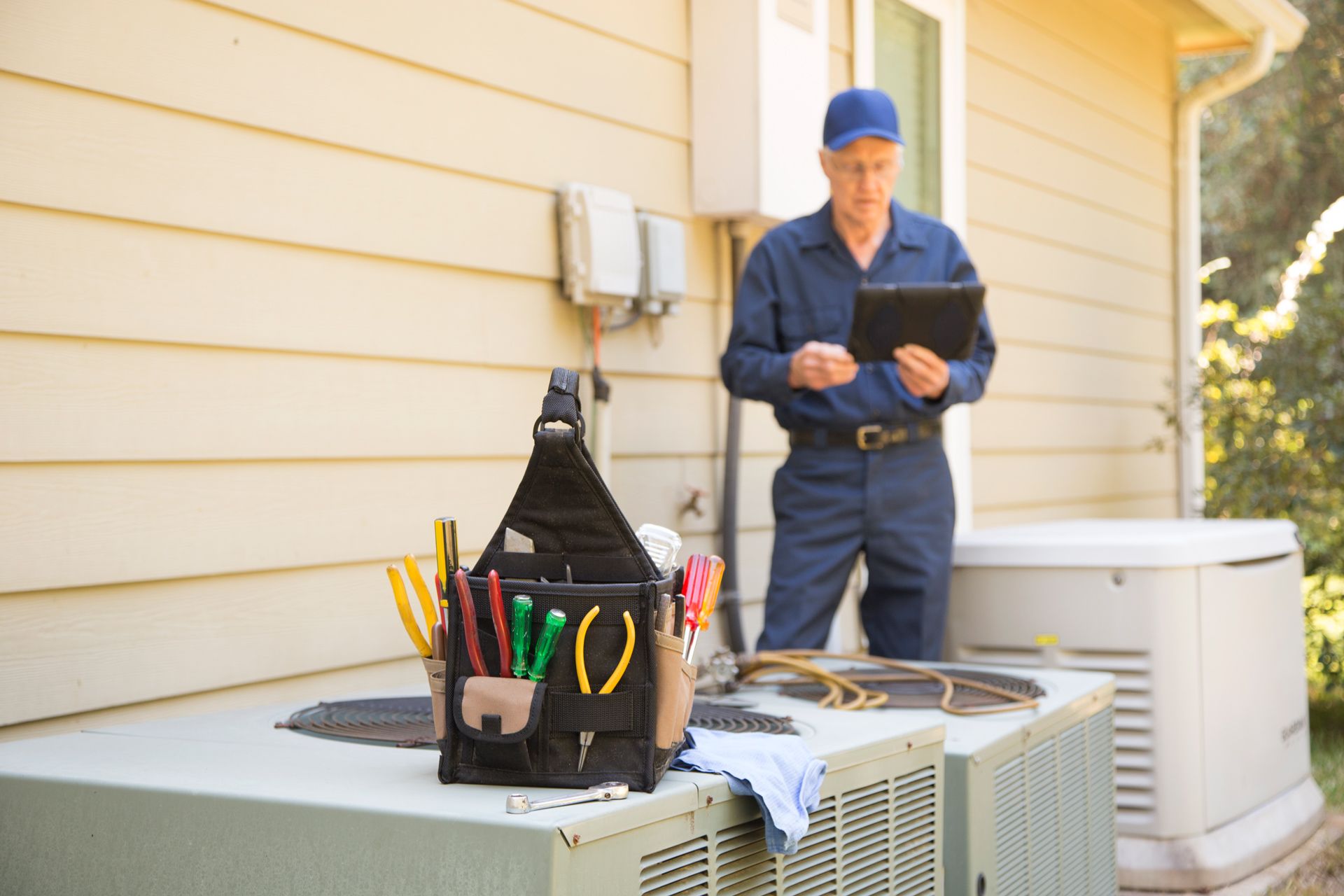 A man is working on an air conditioner outside of a house.
