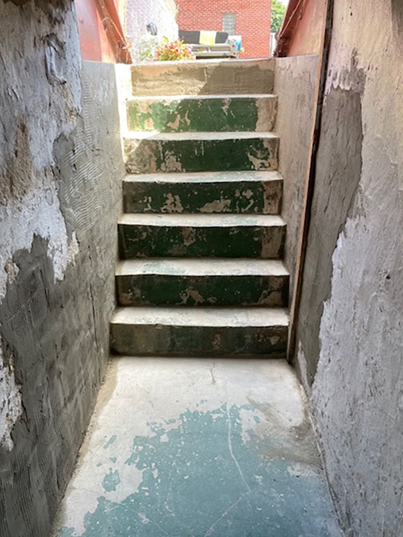 Concrete staircase with chipped green paint, leading upwards.