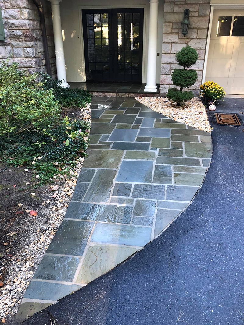 Stone walkway leading to a front door, next to a driveway.