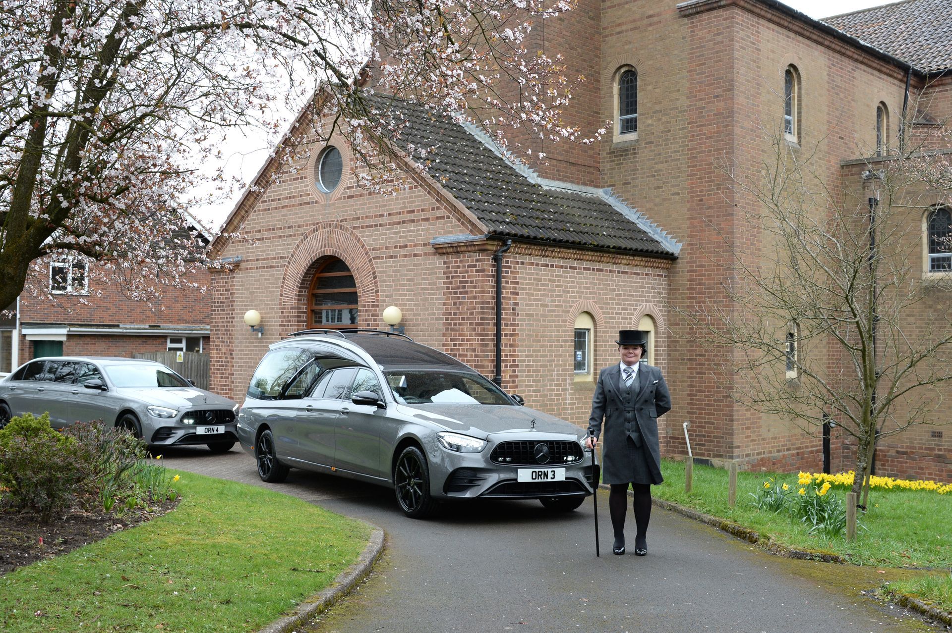 funeral director in front of hearse at a church