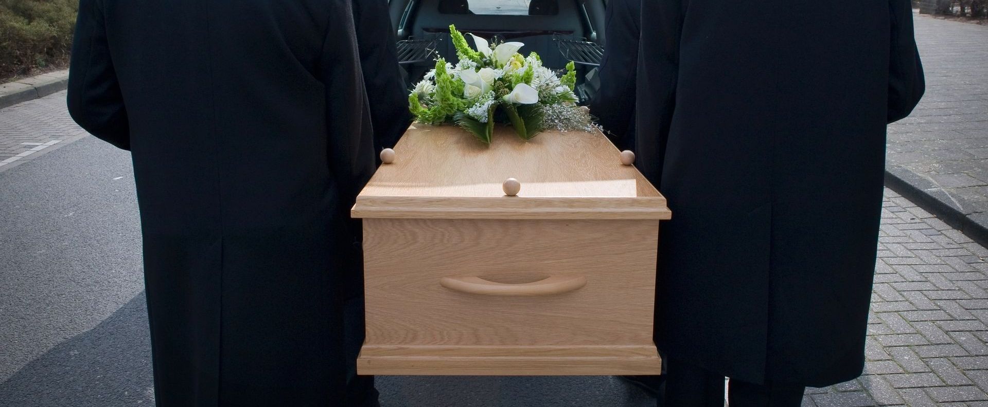 wood casket being put in the hearse