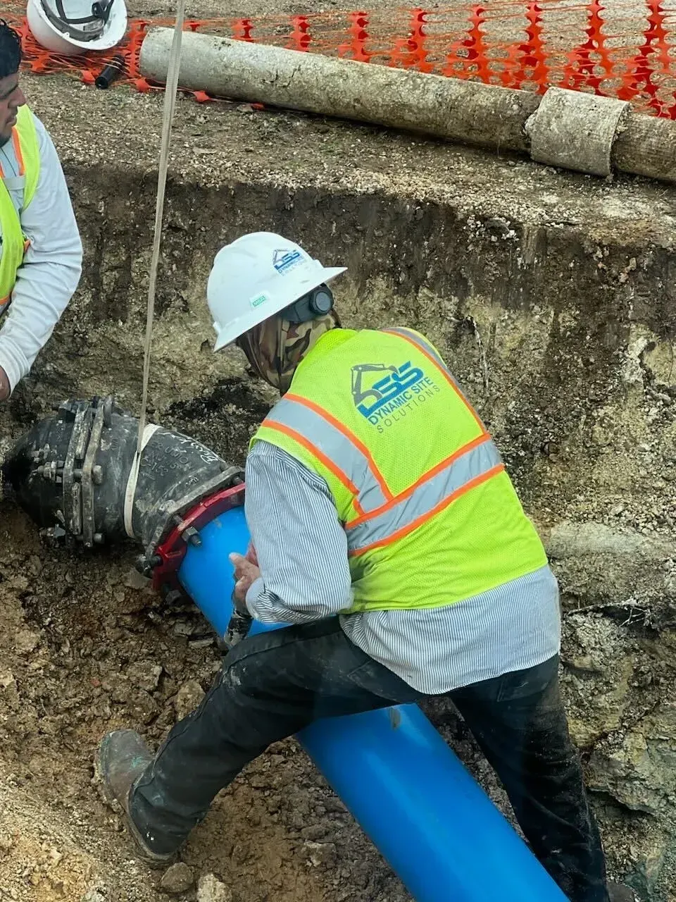 A man wearing a hard hat is working on a blue pipe