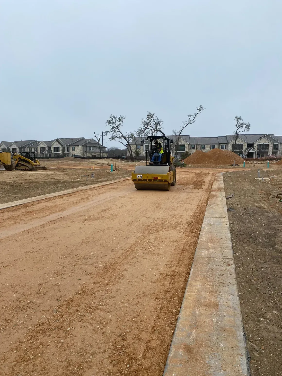 A construction vehicle is driving down a dirt road.