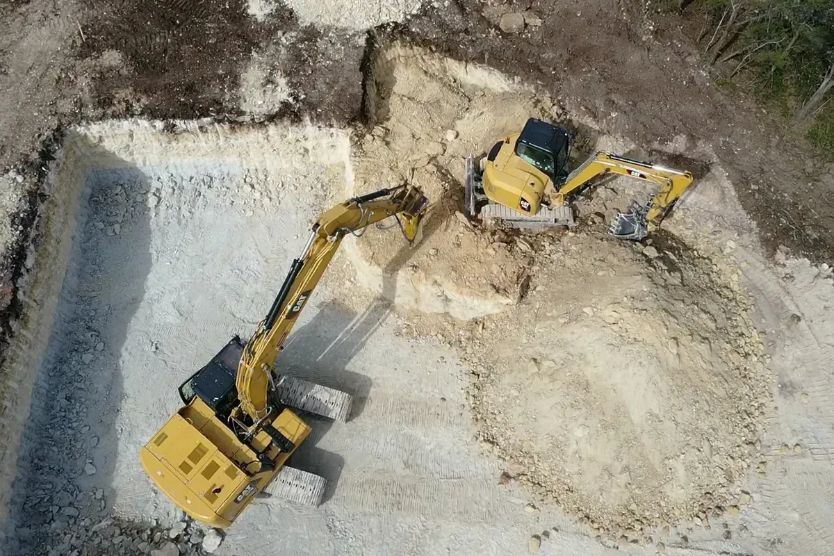 A yellow excavator is digging a hole in the ground.