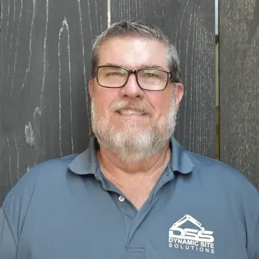 A man with a beard and glasses is wearing a blue shirt.