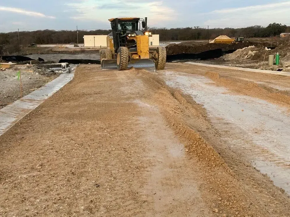 A yellow tractor is driving down a dirt road.