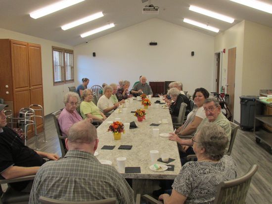 A group of people seated around a long table in a brightly lit room.