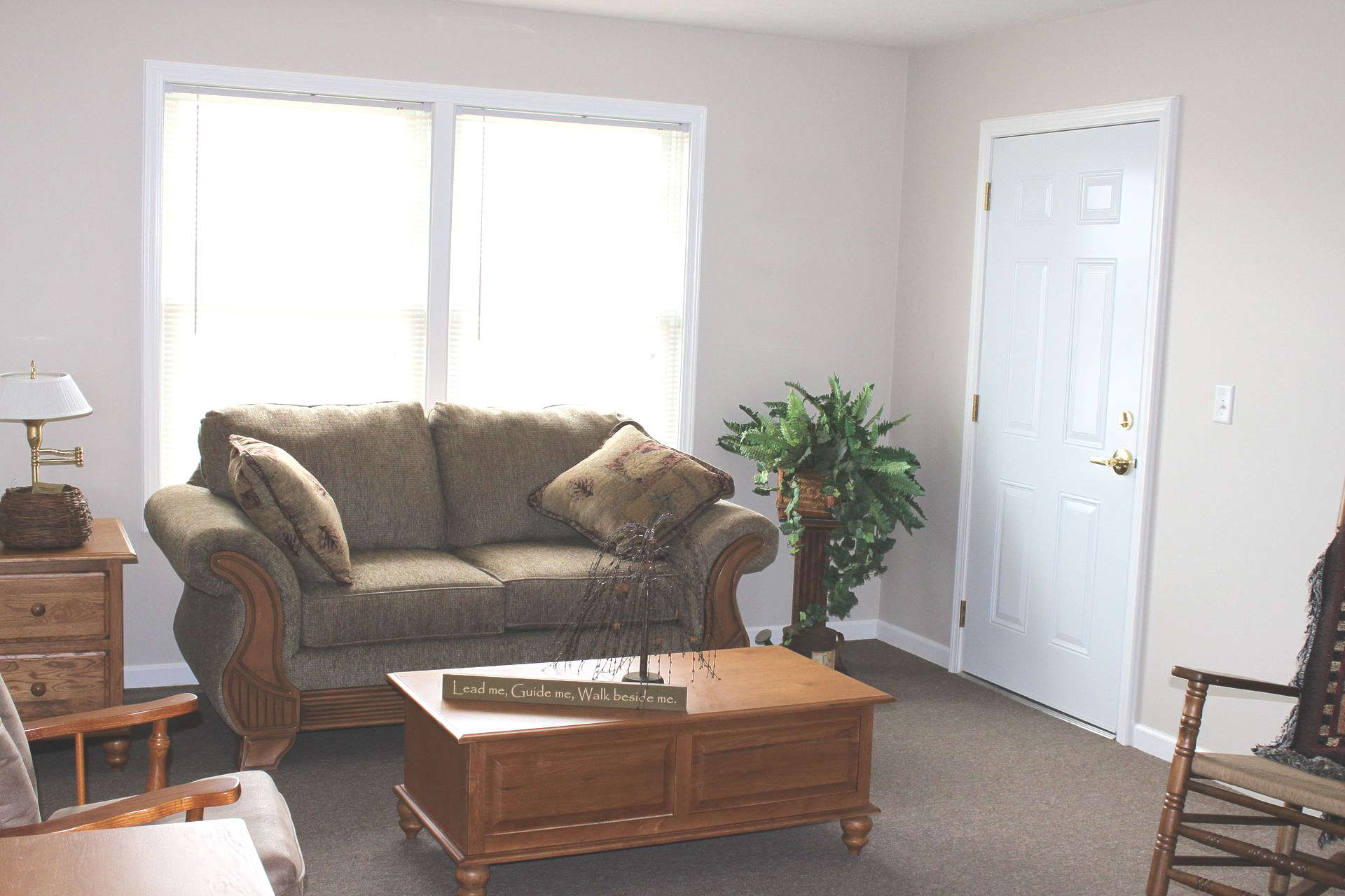 Porch of a brick building with a metal table and chairs, a star, and potted plants.