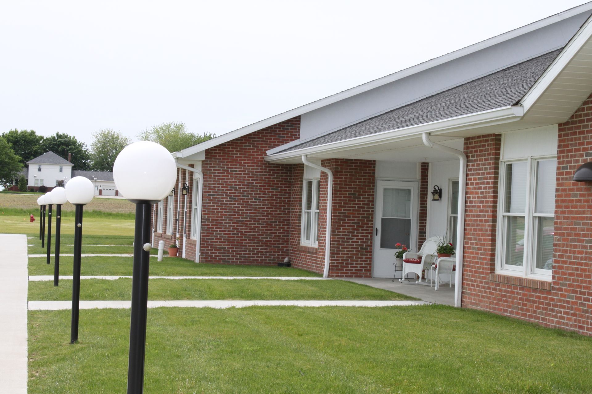Rainbow arches over a residential area with a brick building and parked cars.