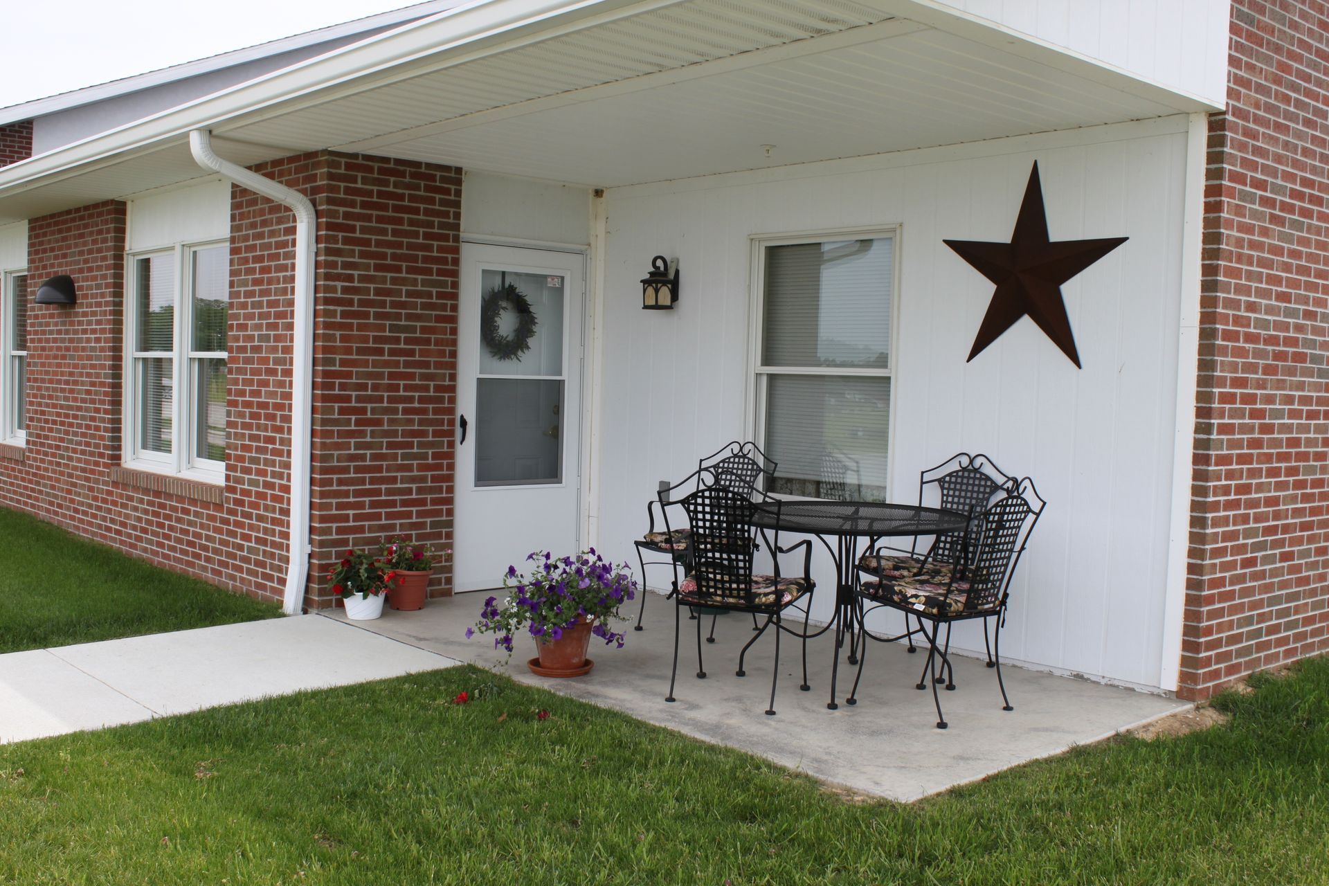 Rainbow arches over a residential area with a brick building and parked cars.