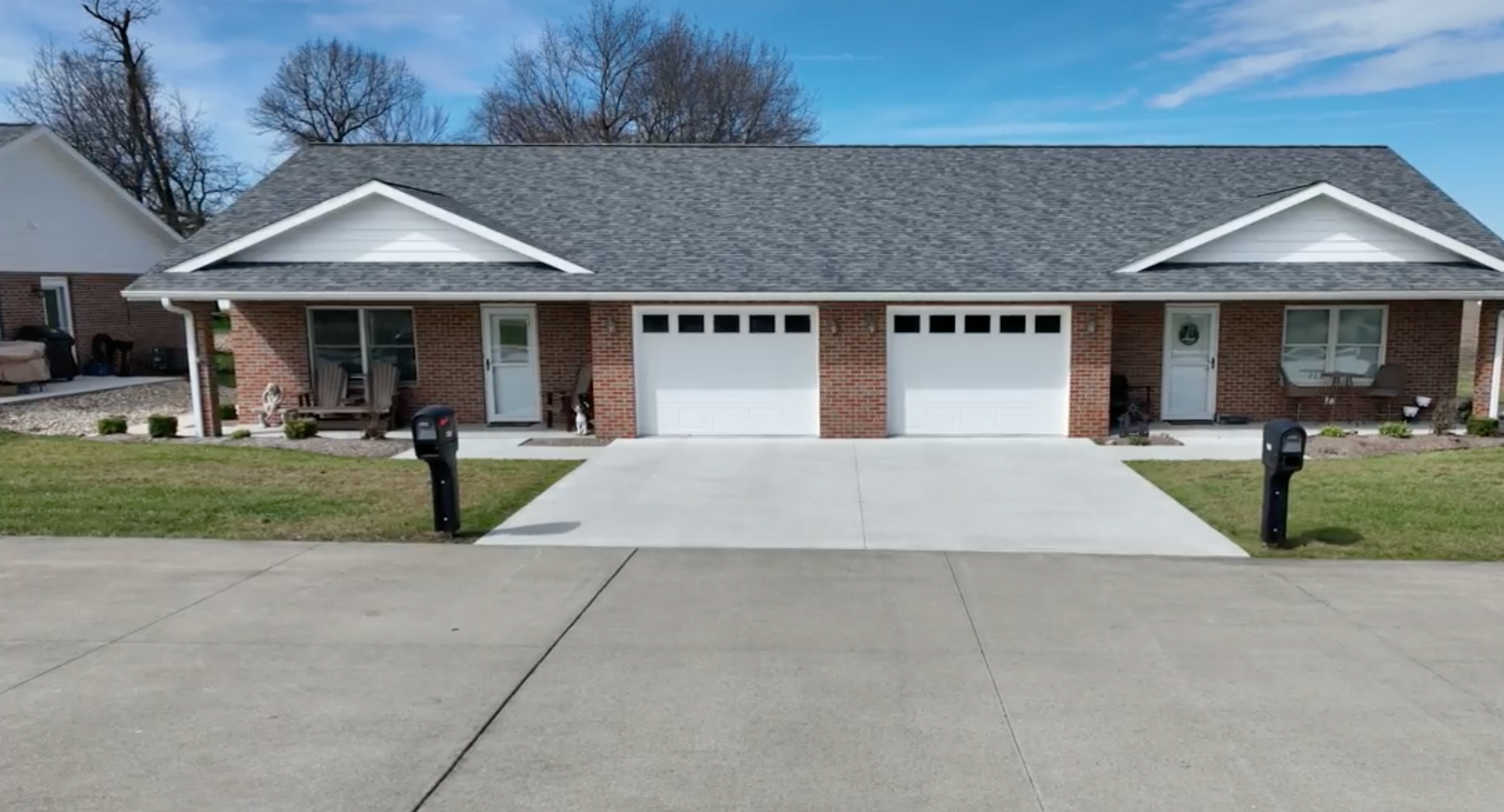 Porch of a brick building with a metal table and chairs, a star, and potted plants.