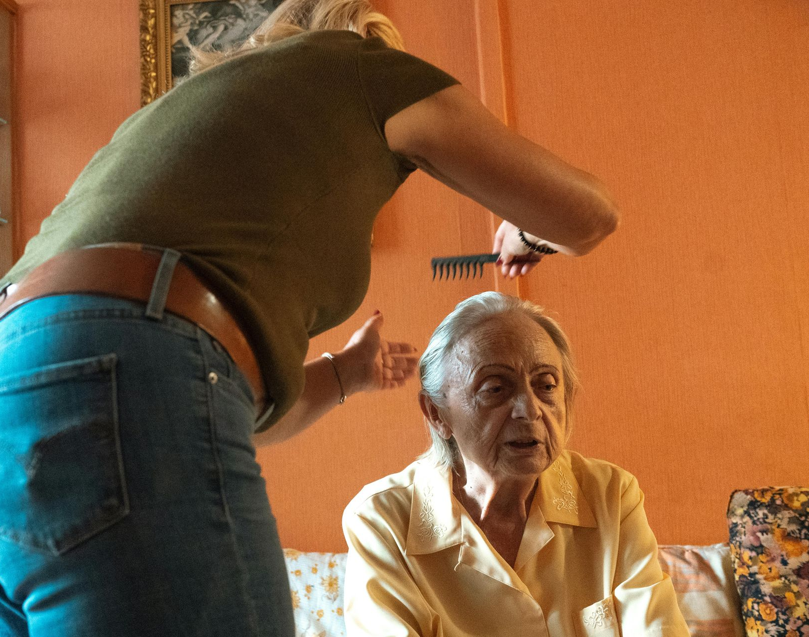 Rainbow arches over a residential area with a brick building and parked cars.