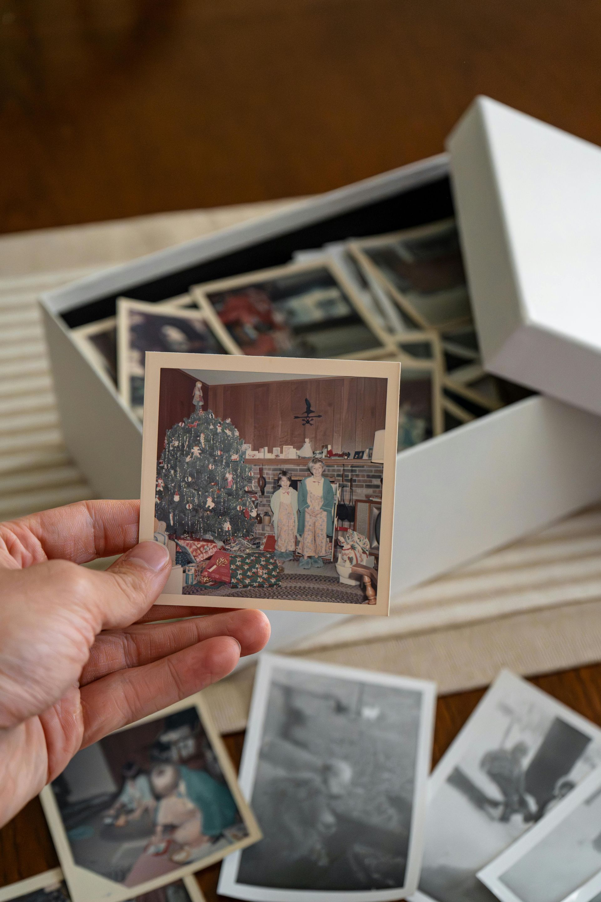 Wooden gazebo in a garden with flowers, a walkway, and a brick building in the background.