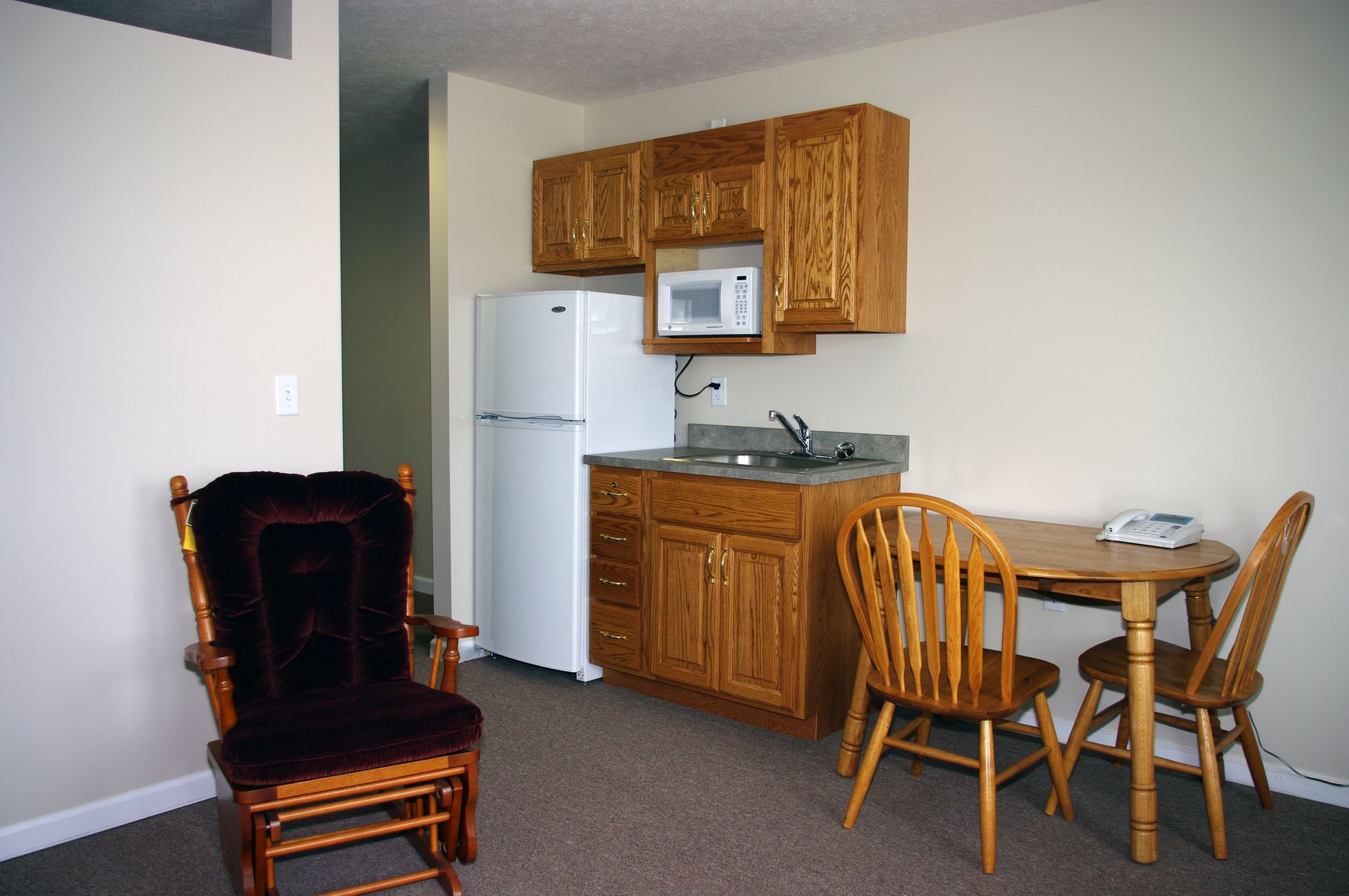 Porch of a brick building with a metal table and chairs, a star, and potted plants.