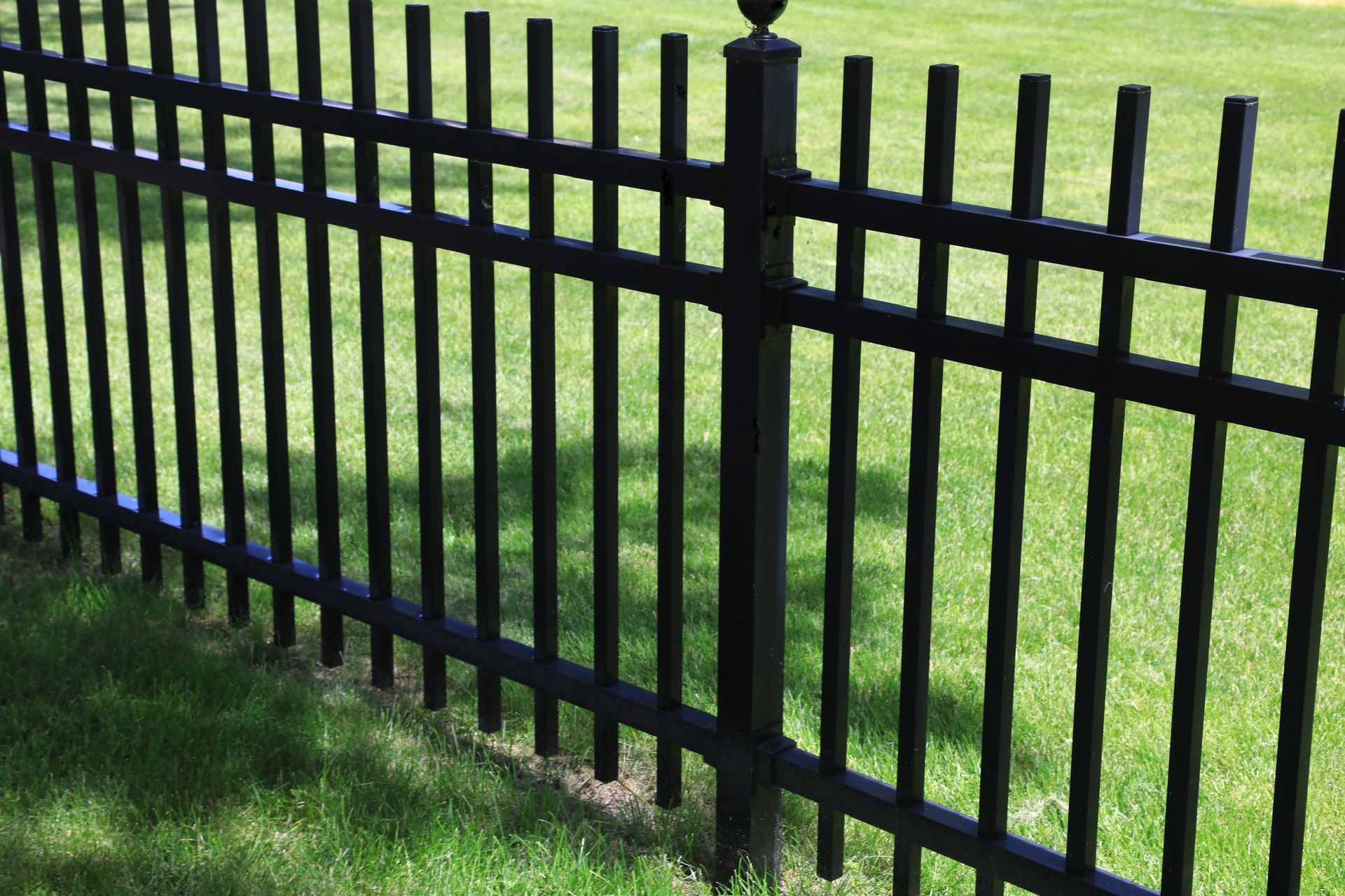 Person wearing red gloves and tool belt, using a drill on a wooden fence outdoors.