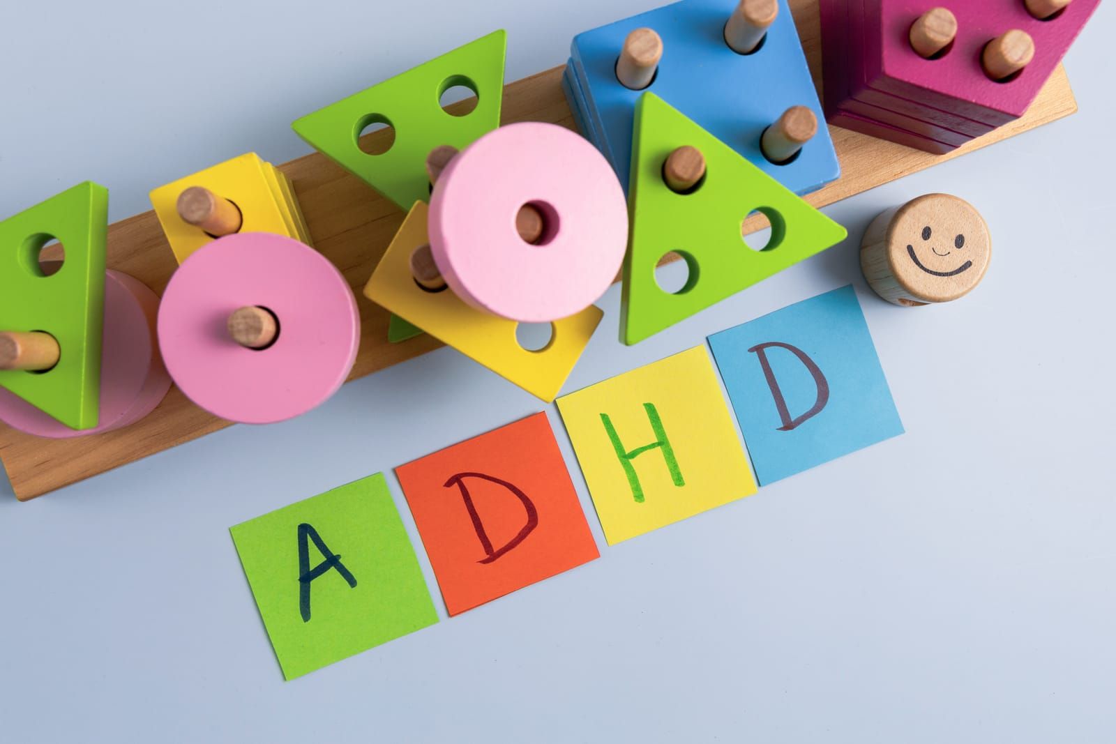 Colorful wooden shape-sorting toy blocks and four square cards on a blue surface, with the letters