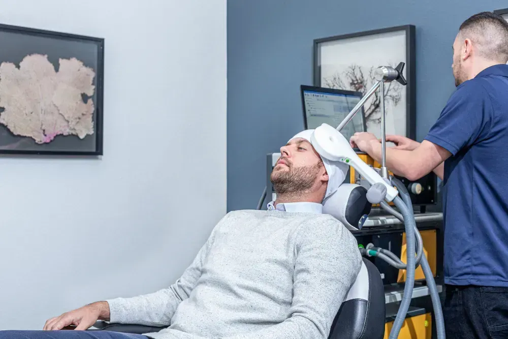 Man receiving transcranial magnetic stimulation treatment in a medical office.
