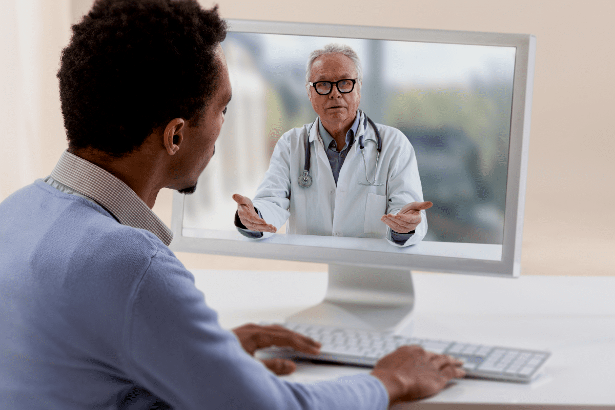Man having a telehealth appointment with a doctor on a computer screen.