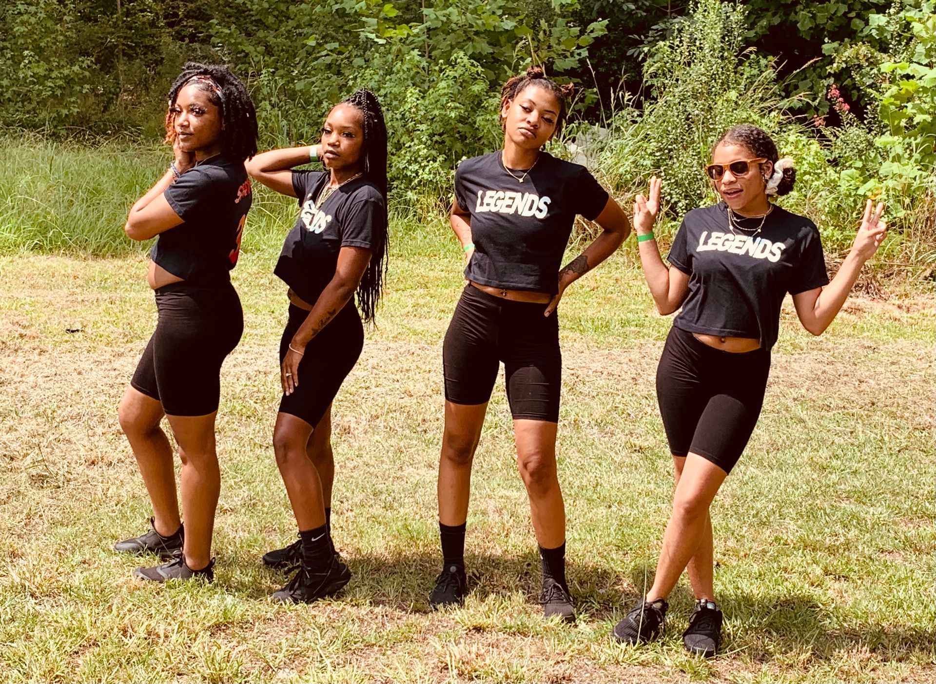 Four of our Dance Members pose outdoors, wearing matching black outfits and