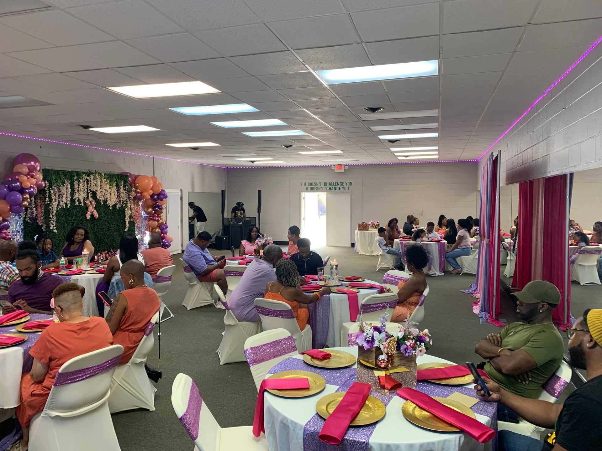 A XMotive Indoor event with round tables, purple/pink decorations, and people seated, socializing.
