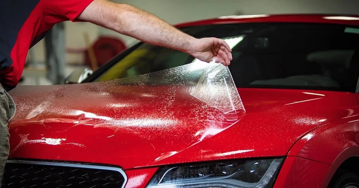 A man is applying a protective film to the hood of a red car. - Fullerton, CA - Ace Auto Tint, Inc.