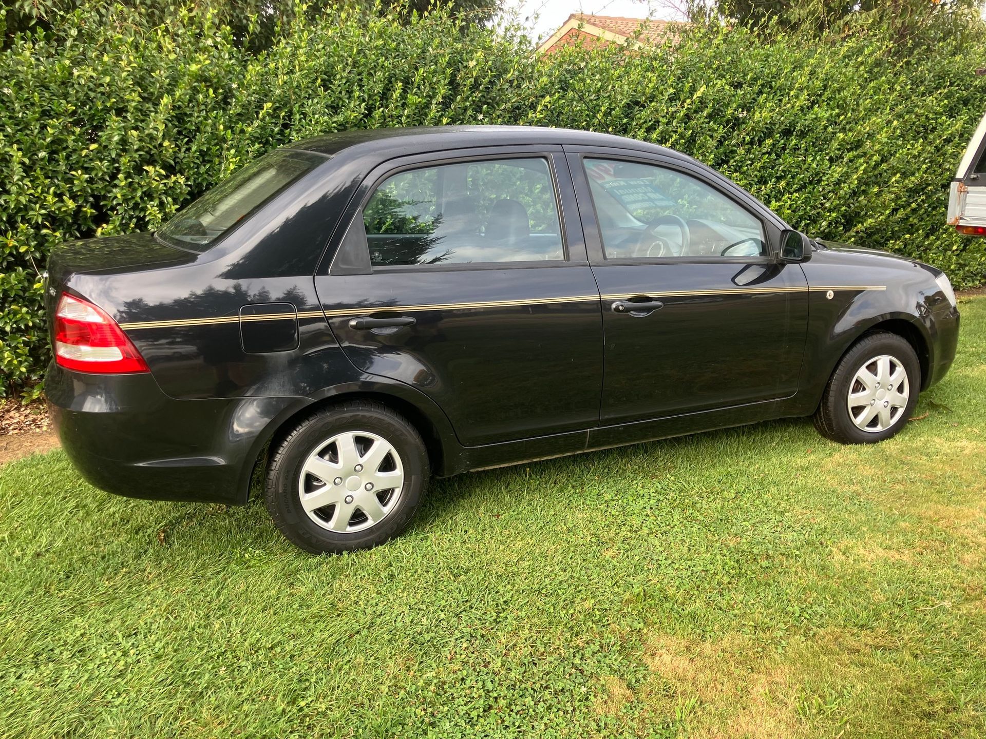 Black Proton Saga Sedan Parked on Green Grass — Great Western Auto Wreckers in Orange, NSW