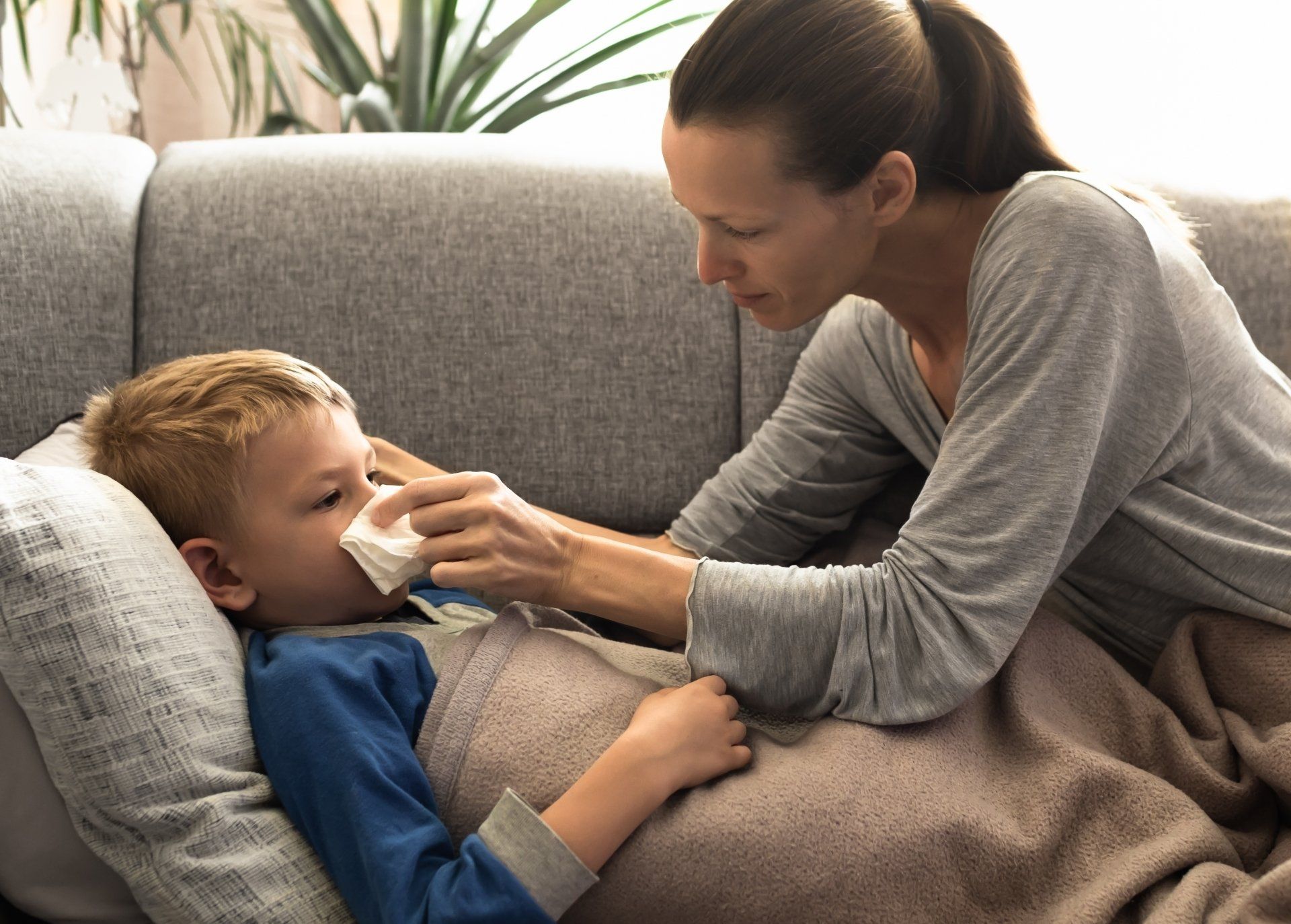 A mother is wiping her sick child's nose with a tissue