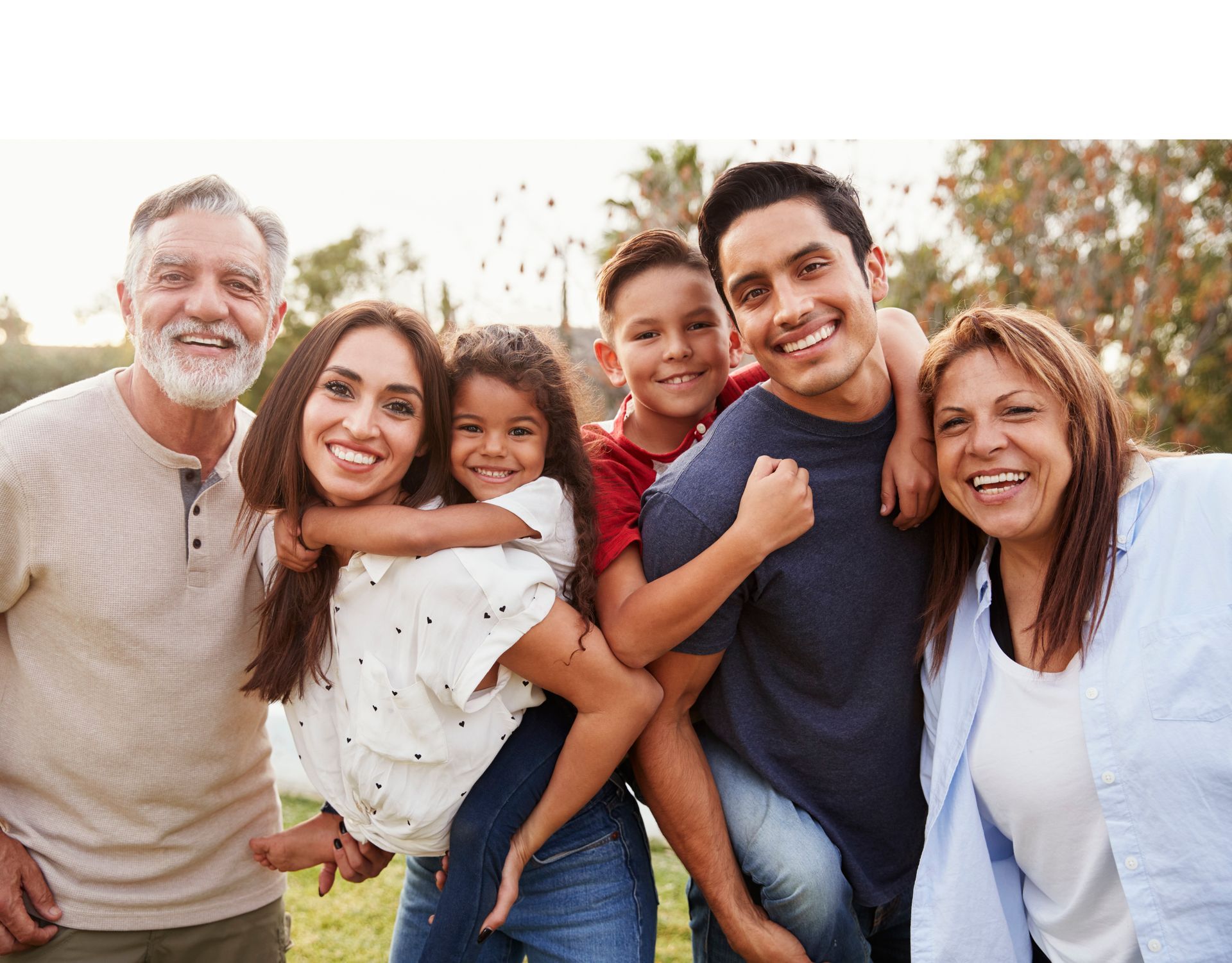 A large family is posing for a picture together in a park.