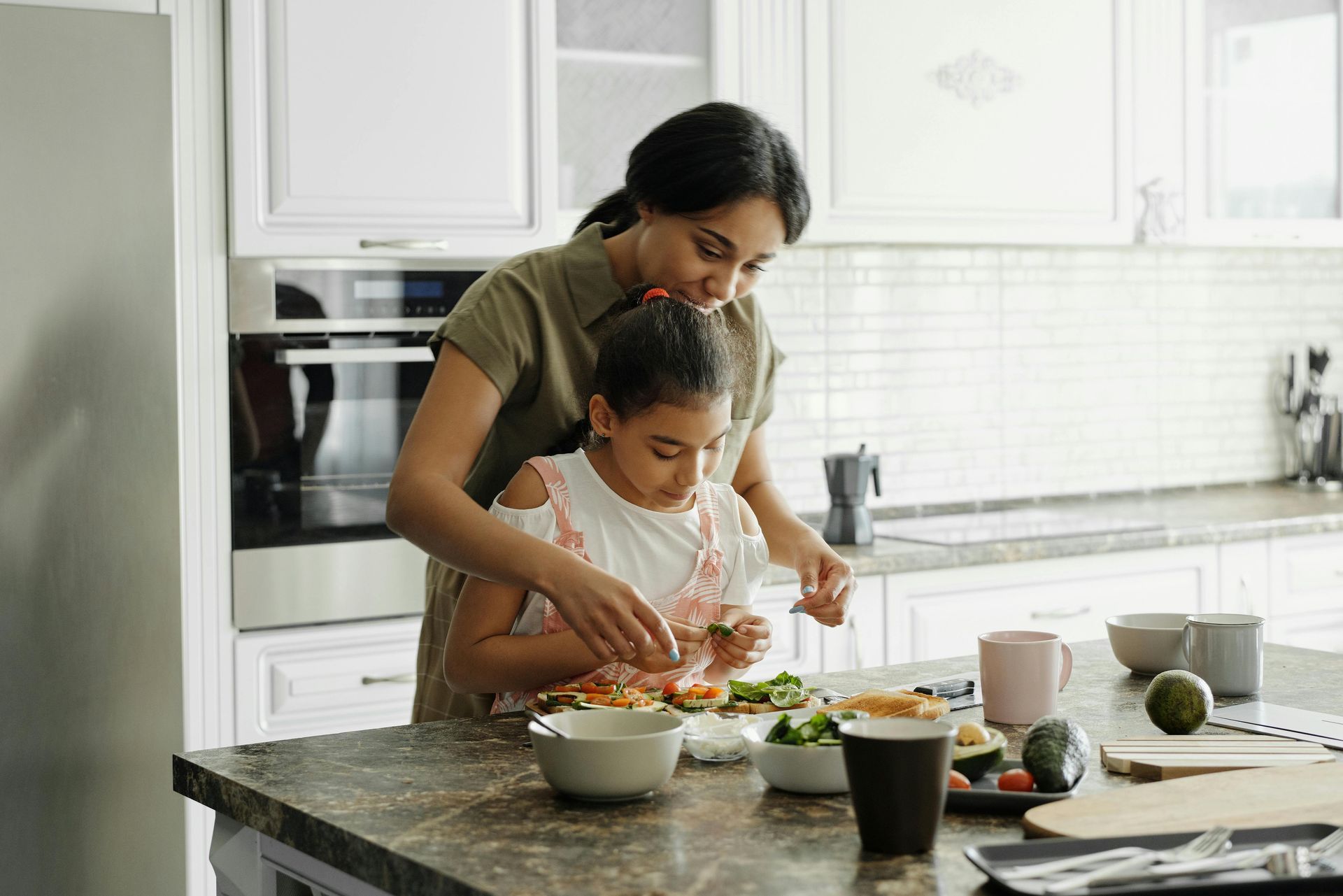 Woman and child preparing food together in a bright kitchen.