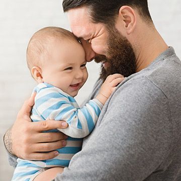 A man with a beard is holding a baby in his arms.