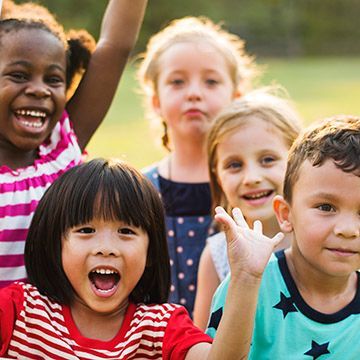 A group of children are posing for a picture in a park.