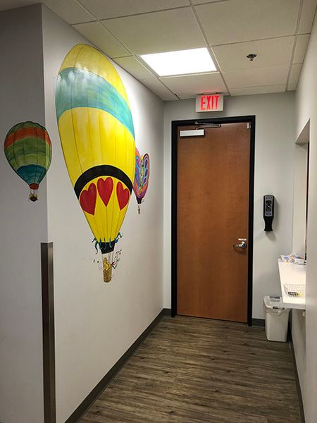 A hallway with a painting of hot air balloons on the wall.