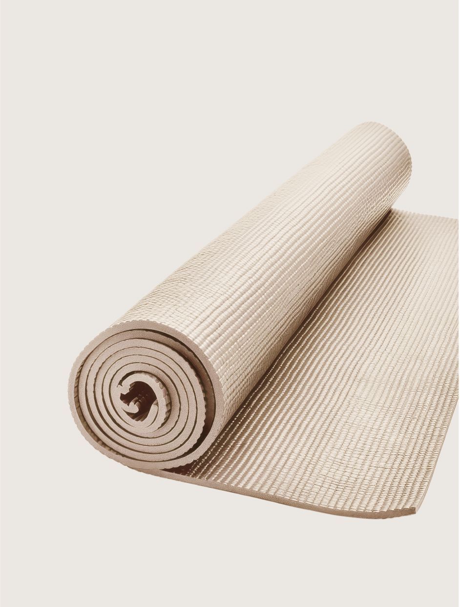 A white yoga mat is rolled up on a white surface.