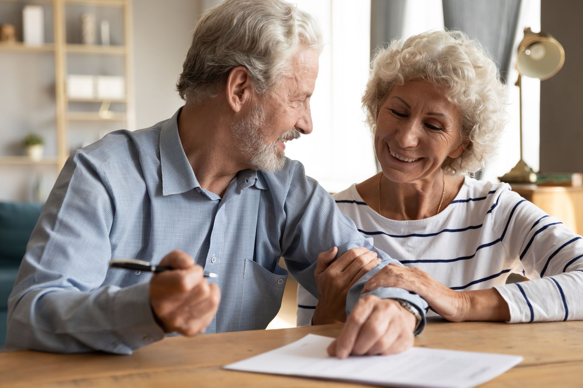 An elderly couple is sitting at a table signing a document.