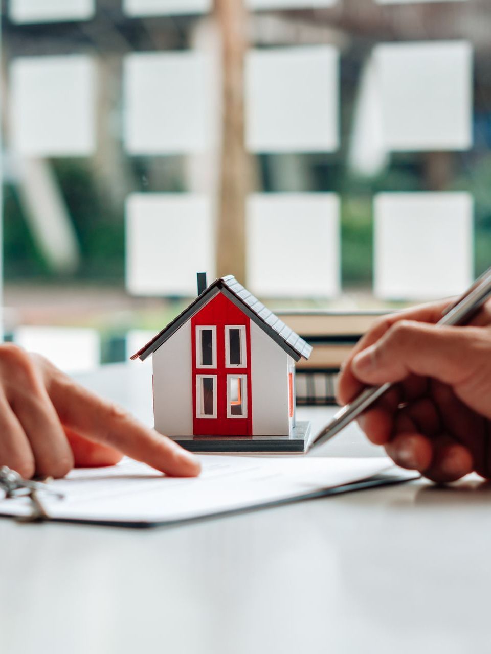 A man is signing a document next to a model house.