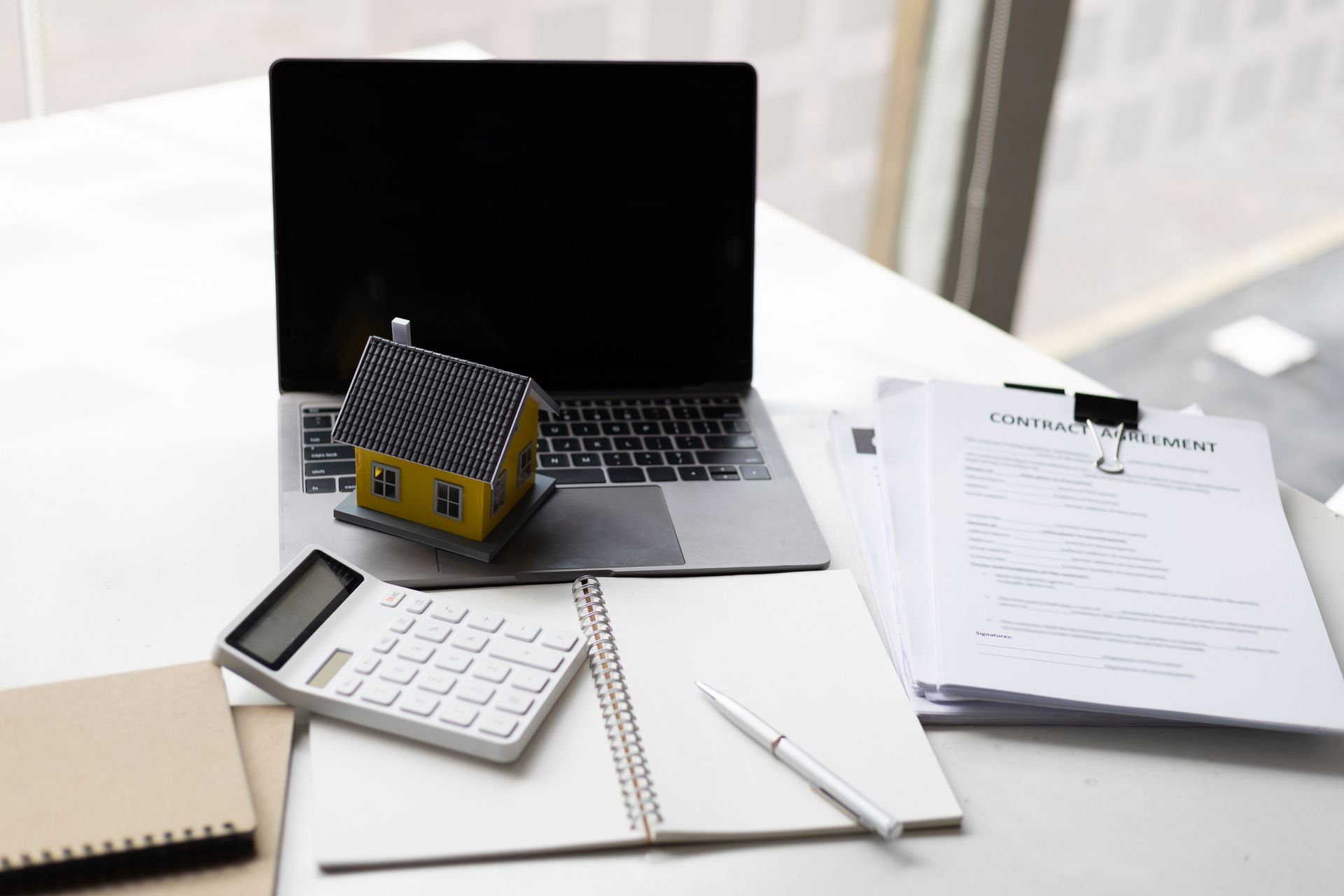 A model house is sitting on top of a laptop computer.