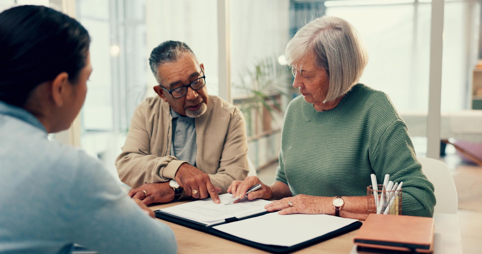 An elderly couple is sitting at a table signing a document.