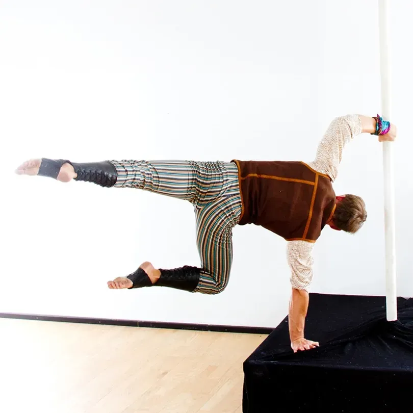 Milanus Circus, Miami, FL, pole entertainer with leg extension.