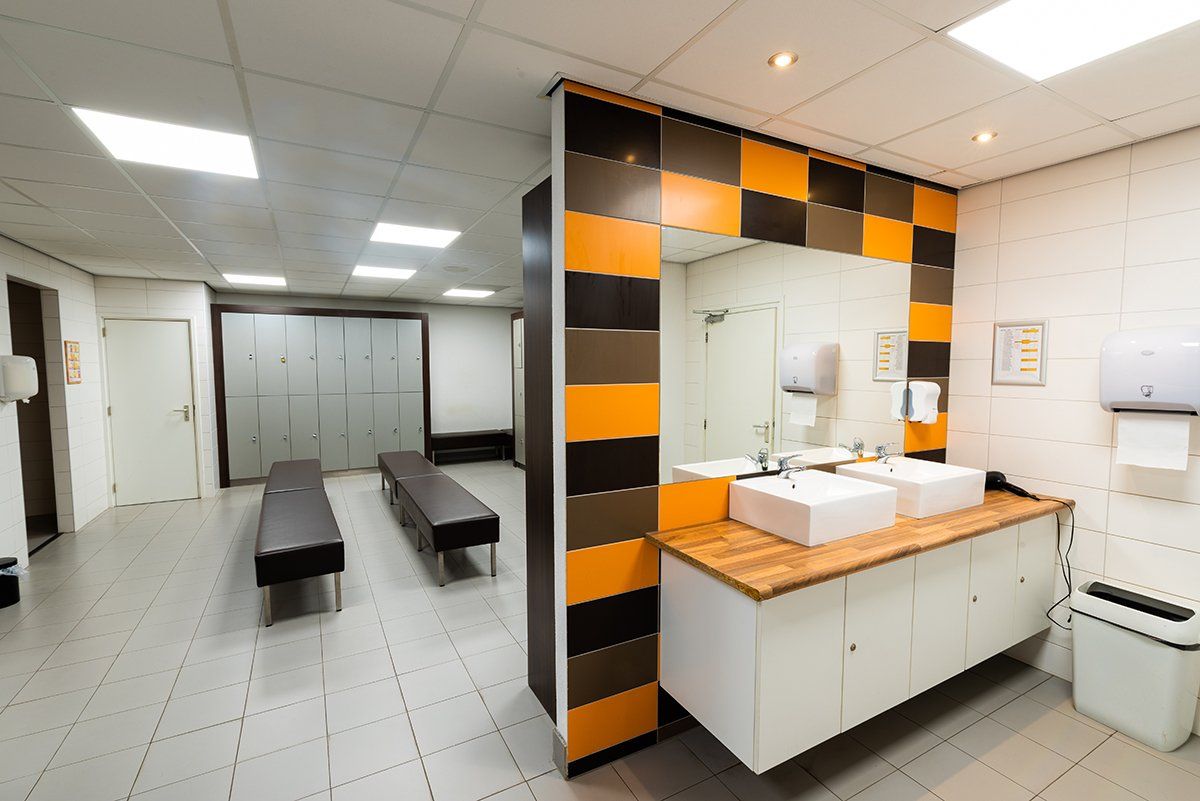 Een kleedkamer met twee wastafels en een spiegel.