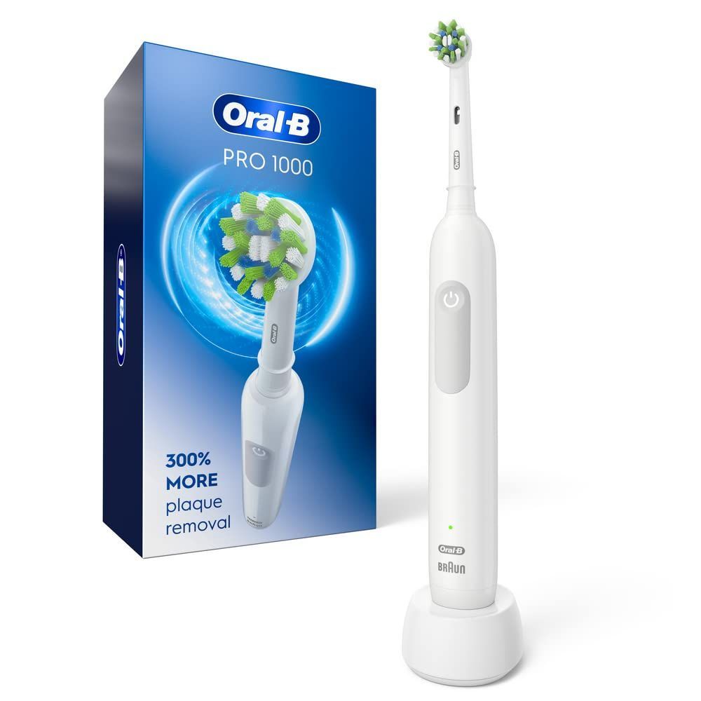 Oral-B Pro 1000 electric toothbrush standing in its charger, next to the product packaging.