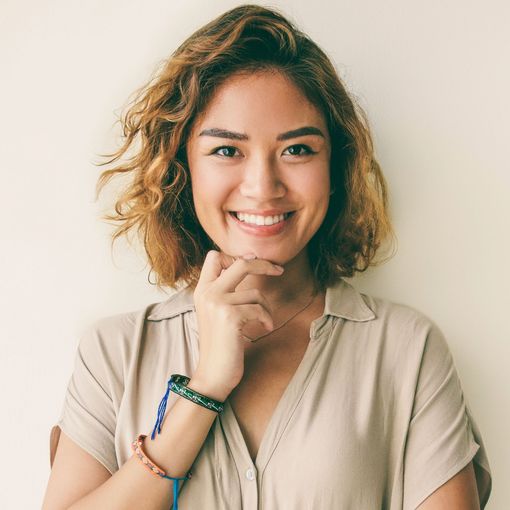 A woman is smiling with her hand on her chin.